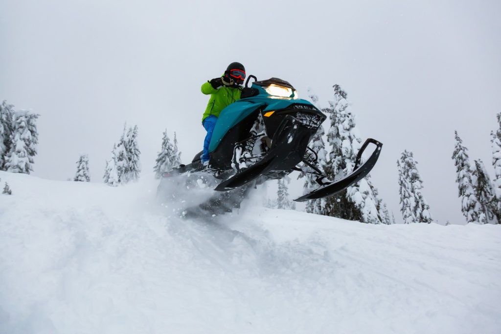 Adventurous Man Riding a Snowmobile in white snow